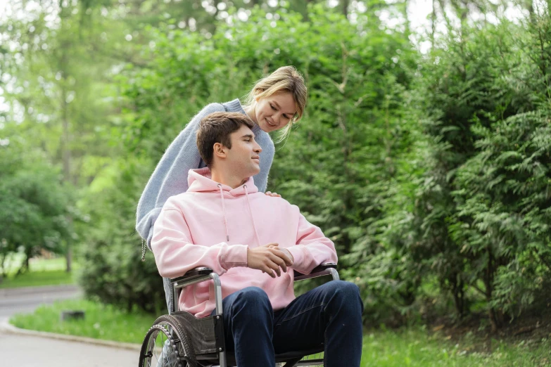 the man is sitting in a wheel chair next to the woman