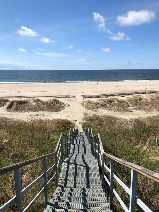 a staircase leading down to the beach with a view of the ocean