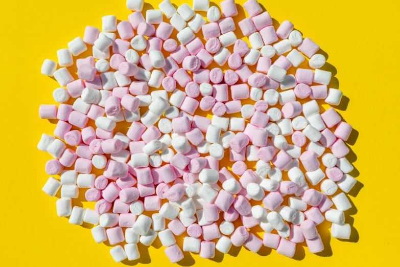 the candy marshmallows are scattered around on the yellow surface