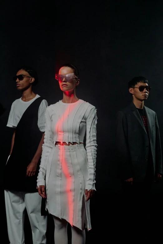 a model stands with two other models on the catwalk