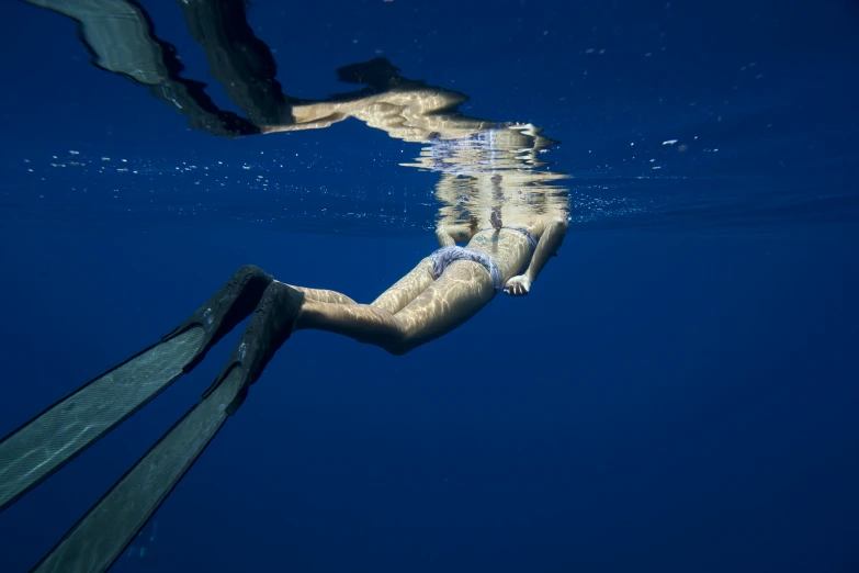 a person is swimming under the water with only their feet propped up