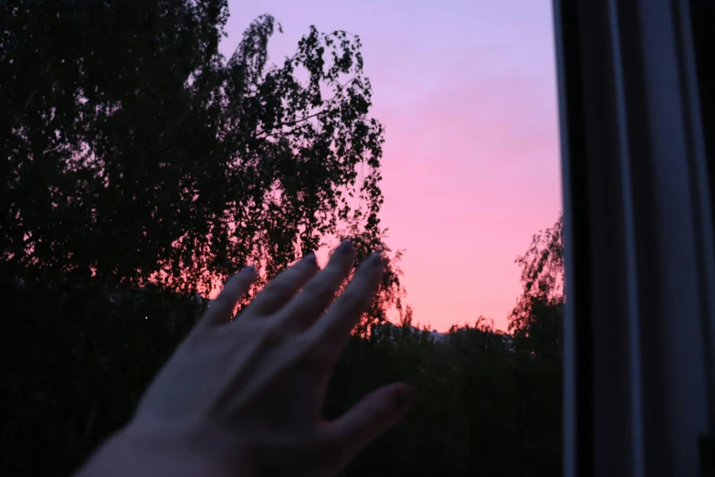the hand is pointing out the window at the sun