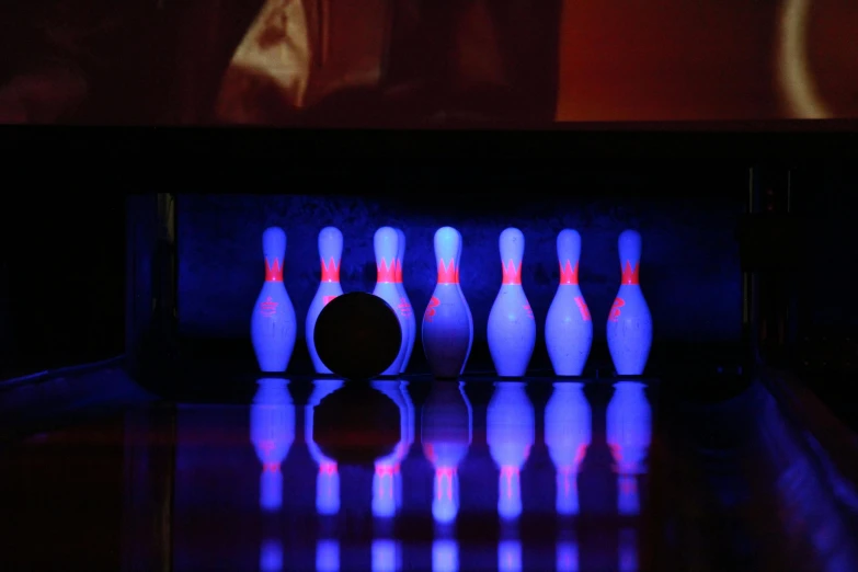 glowing bowling pins and a bowling ball on a black table