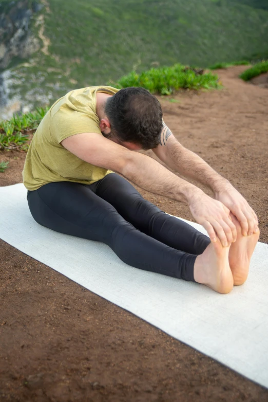 man sitting on a yoga mat with his feet down