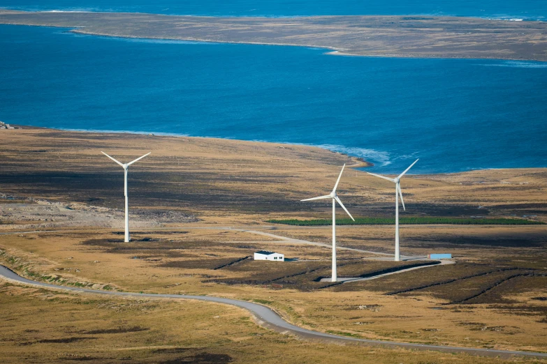 three wind turbines stand on a dry grass field