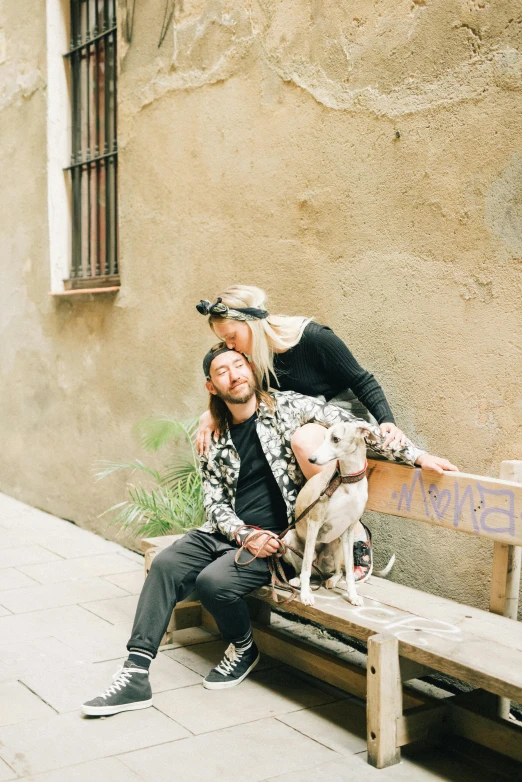 a man and woman sit on a bench with a dog