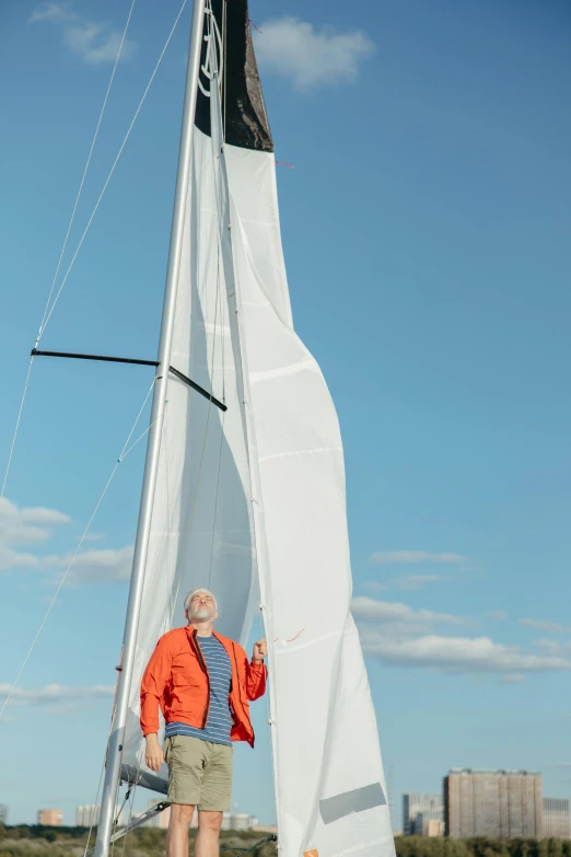 a man standing near a sail boat at the beach