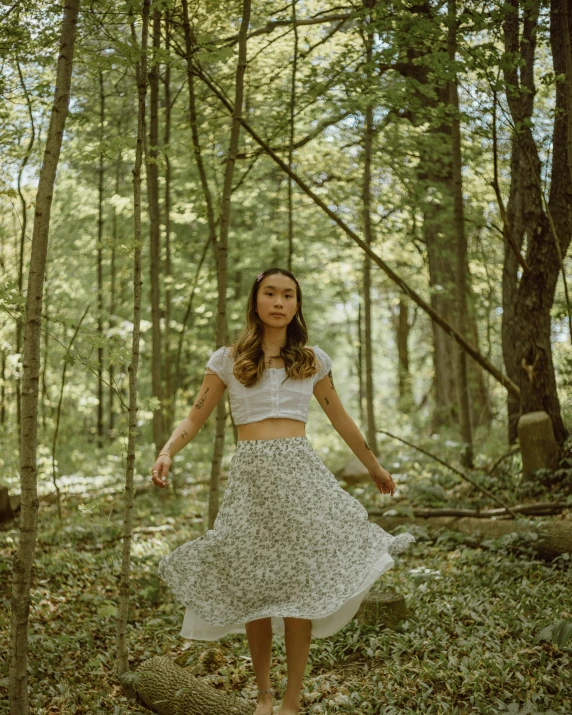 a young woman wearing a skirt is in the woods