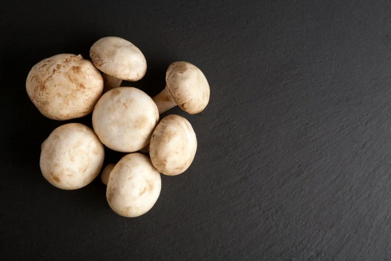 some white mushrooms are sitting on a black table