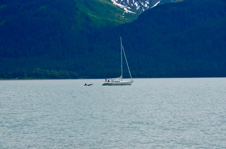 a sail boat out on the water with mountains in the background