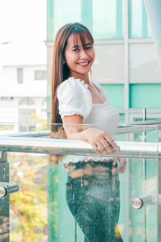 the woman is standing on the outside glass railing smiling