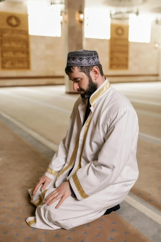 a man wearing a white outfit and kneeling down