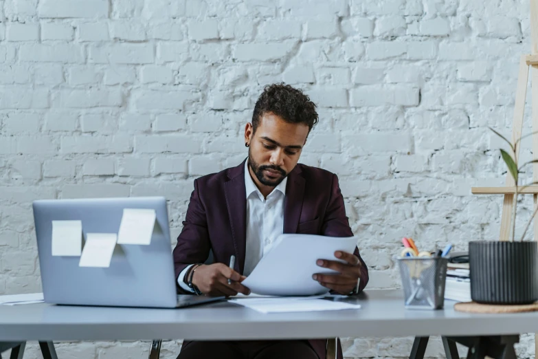 a man with his face in his hands while looking at a piece of paper