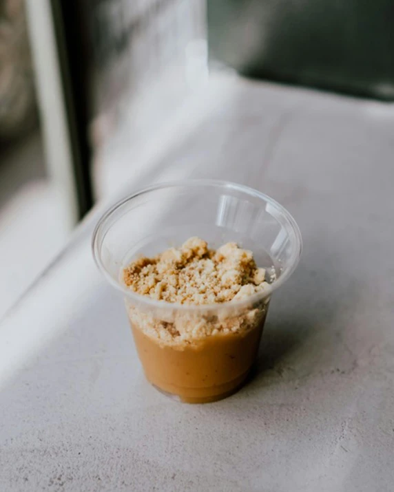 a small takeout cup with coffee crumbles sits on a countertop