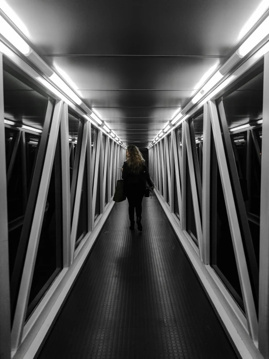 a person walking across a bridge in black and white