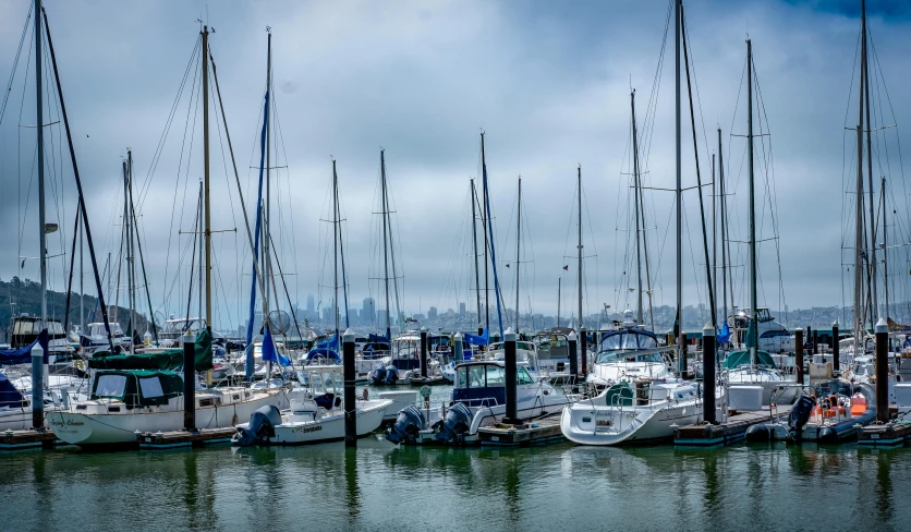 many boats are docked on the water with some wires sticking out of them