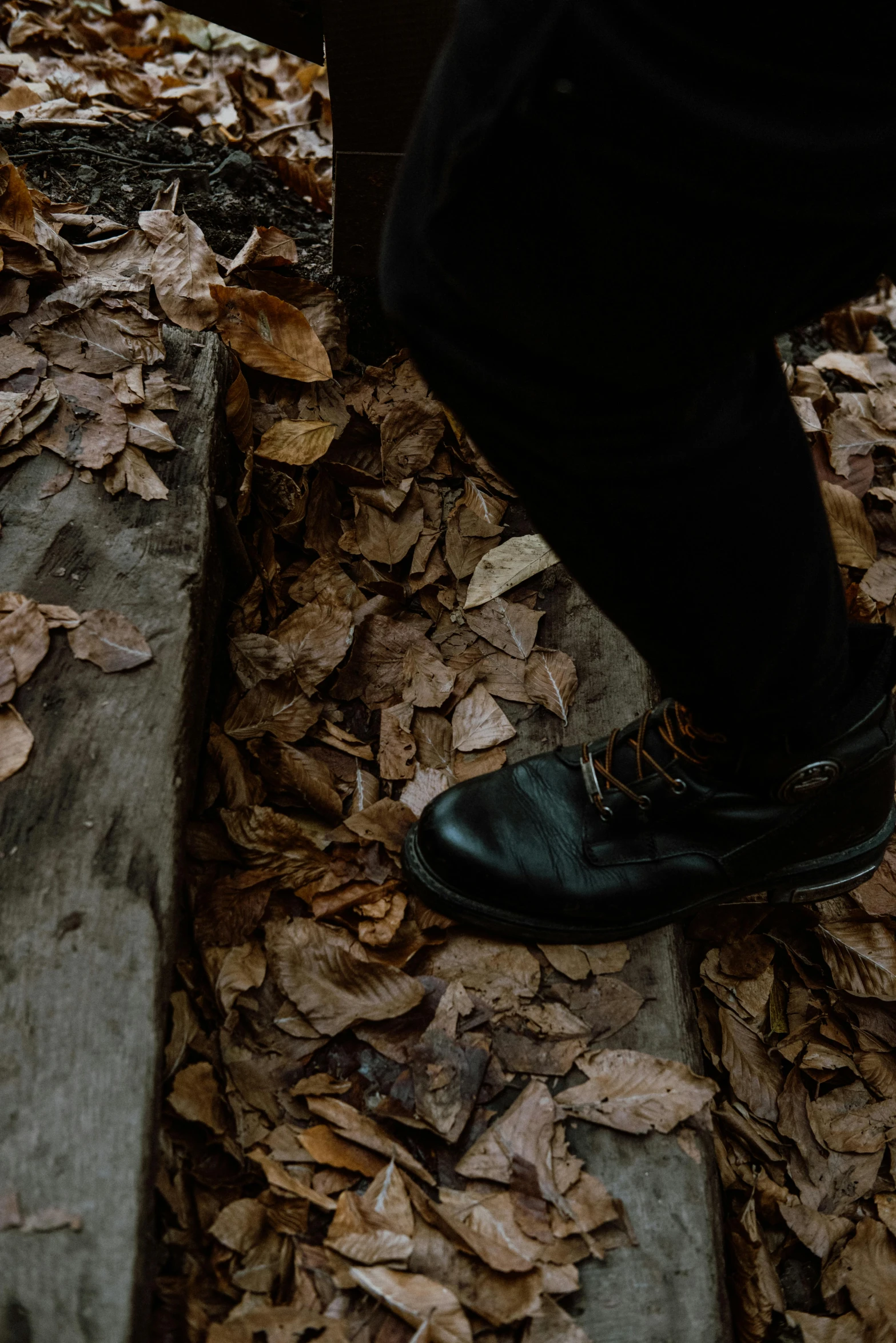 the foot and ankles of a person who is standing in leafy area