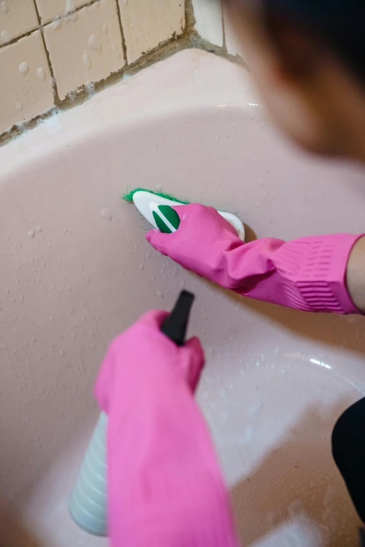 a person wearing pink gloves and holding a green item