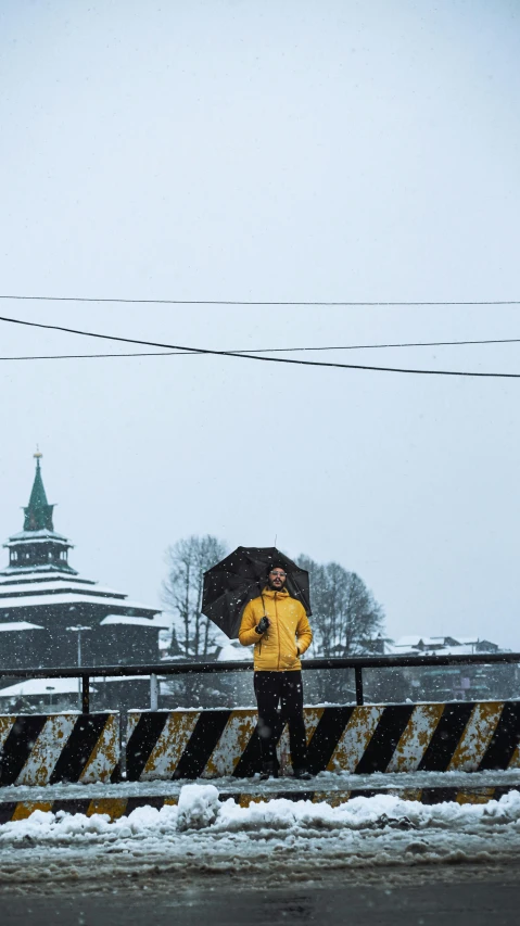 a person in yellow coat holding an umbrella and walking on bridge