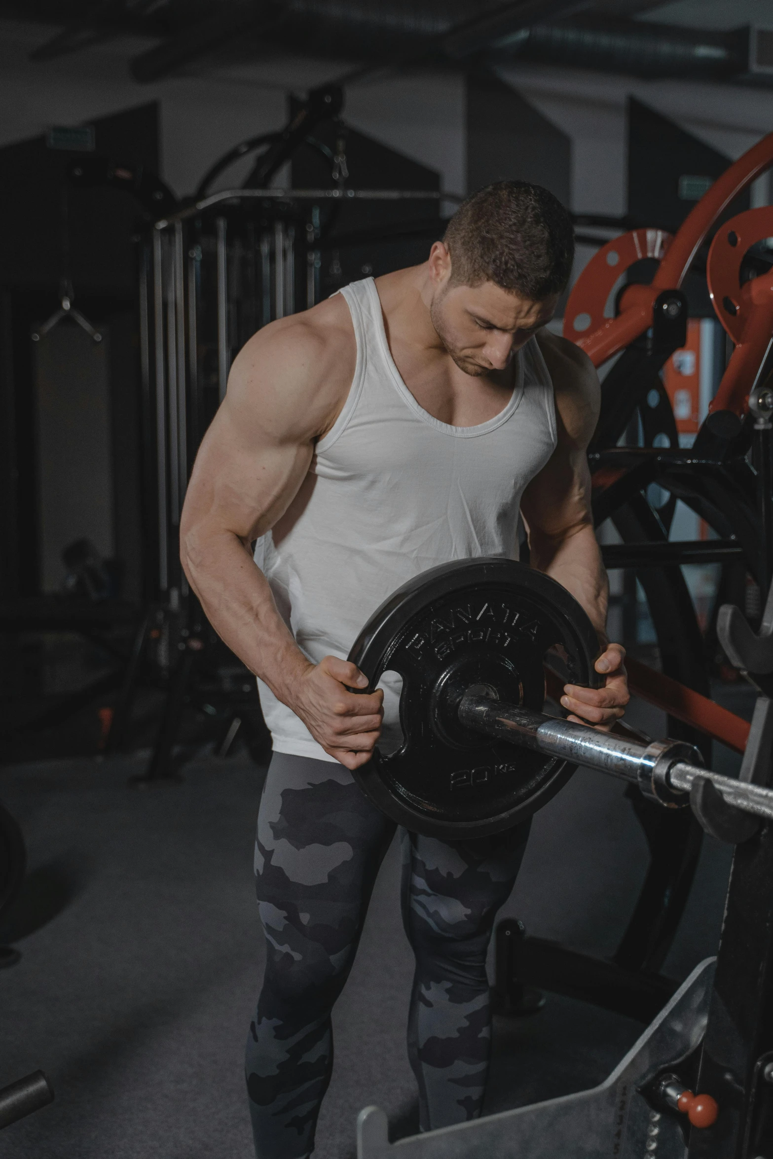 a man holding a gym bar while wearing leggings