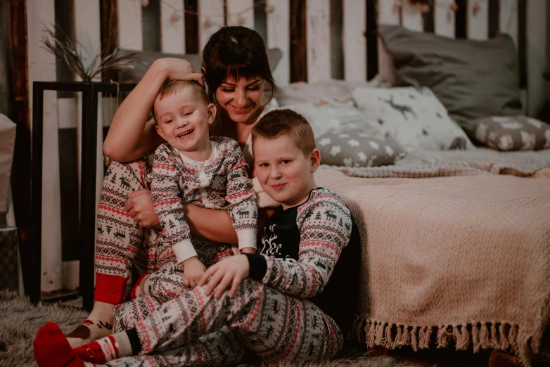 a mother, her two boys and their dog sitting in a bedroom
