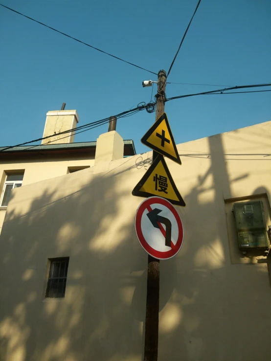 two different warning signs on a pole in front of a building