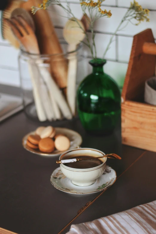 a table with cups of coffee, biscuits and spoons