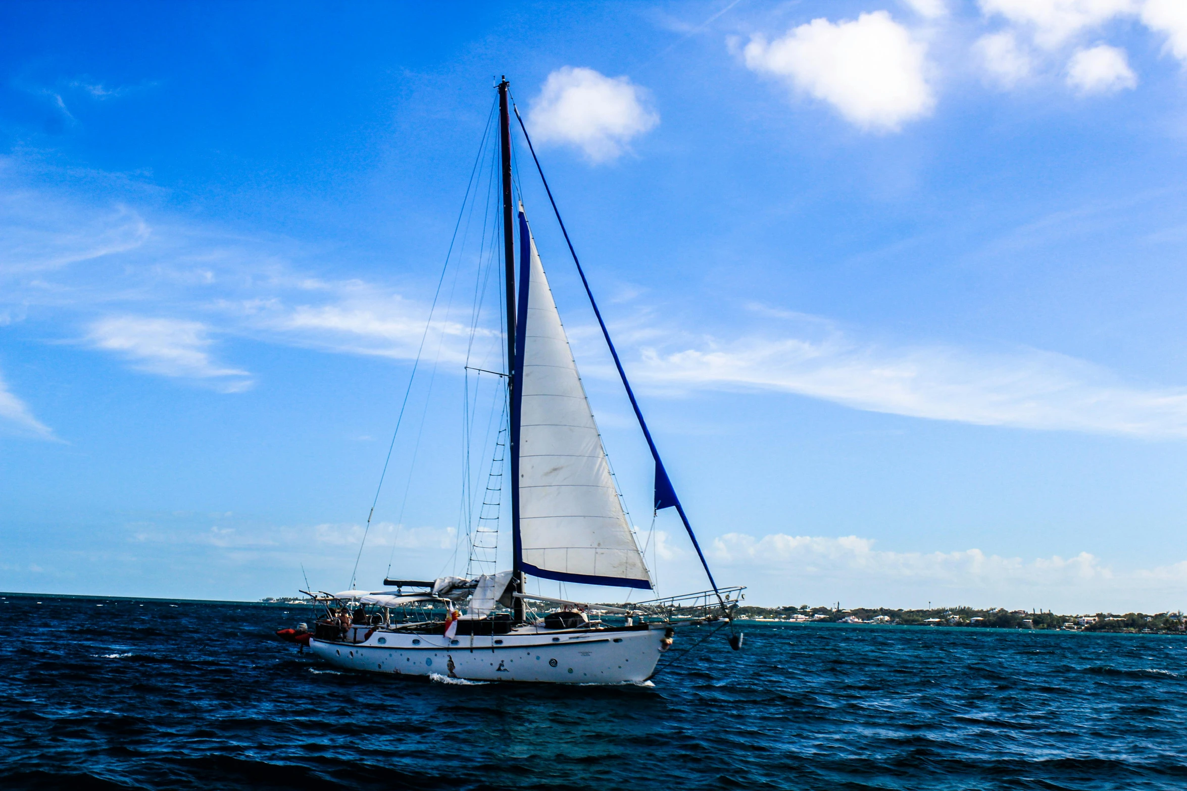 sailboat floating in the water with clouds overhead