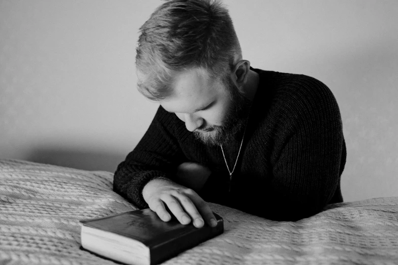 man looking at an open book on a bed