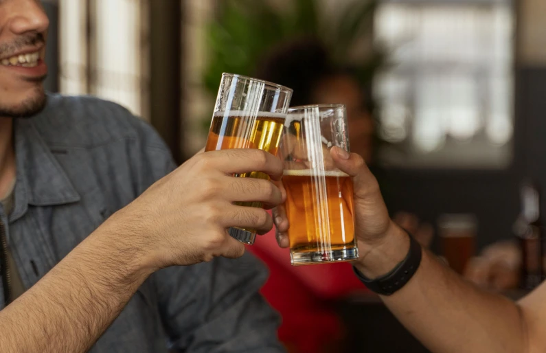 people clinking with glasses and holding beer in their hands