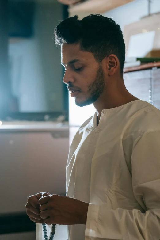 a man in a white outfit holding a rosary