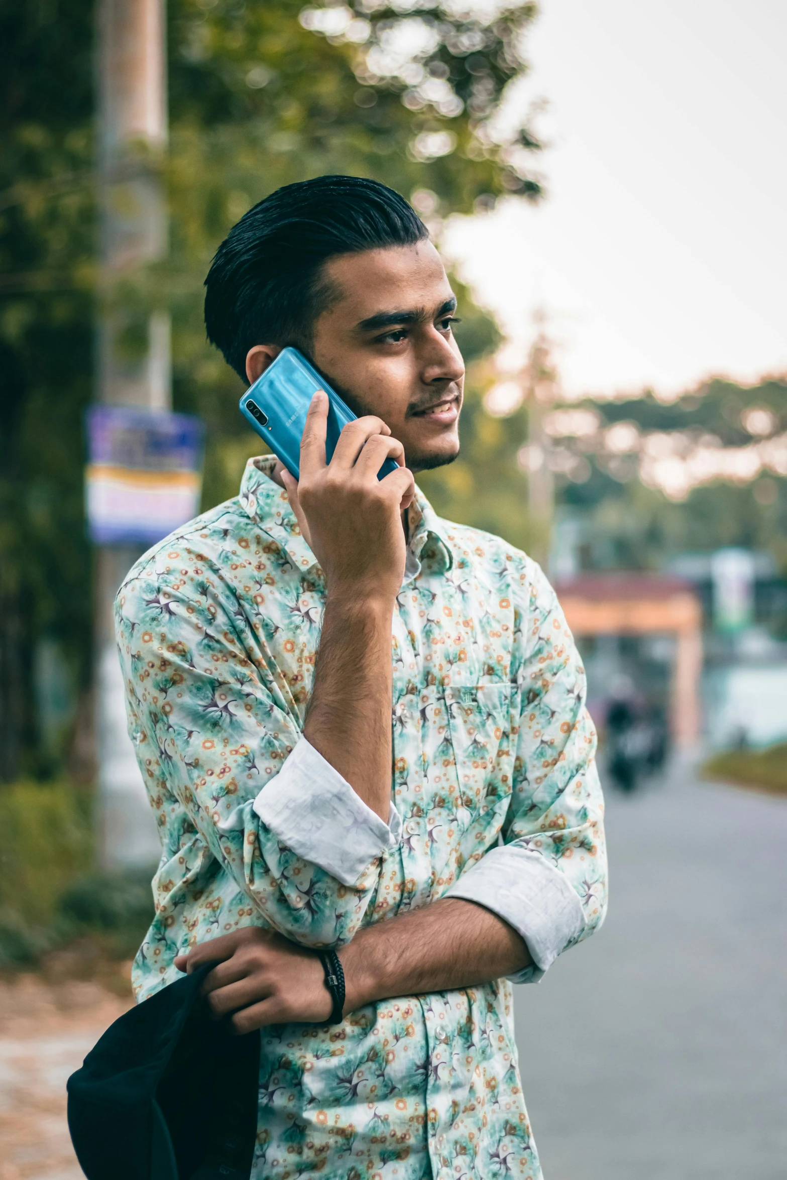 a man with a flower shirt talking on a cell phone