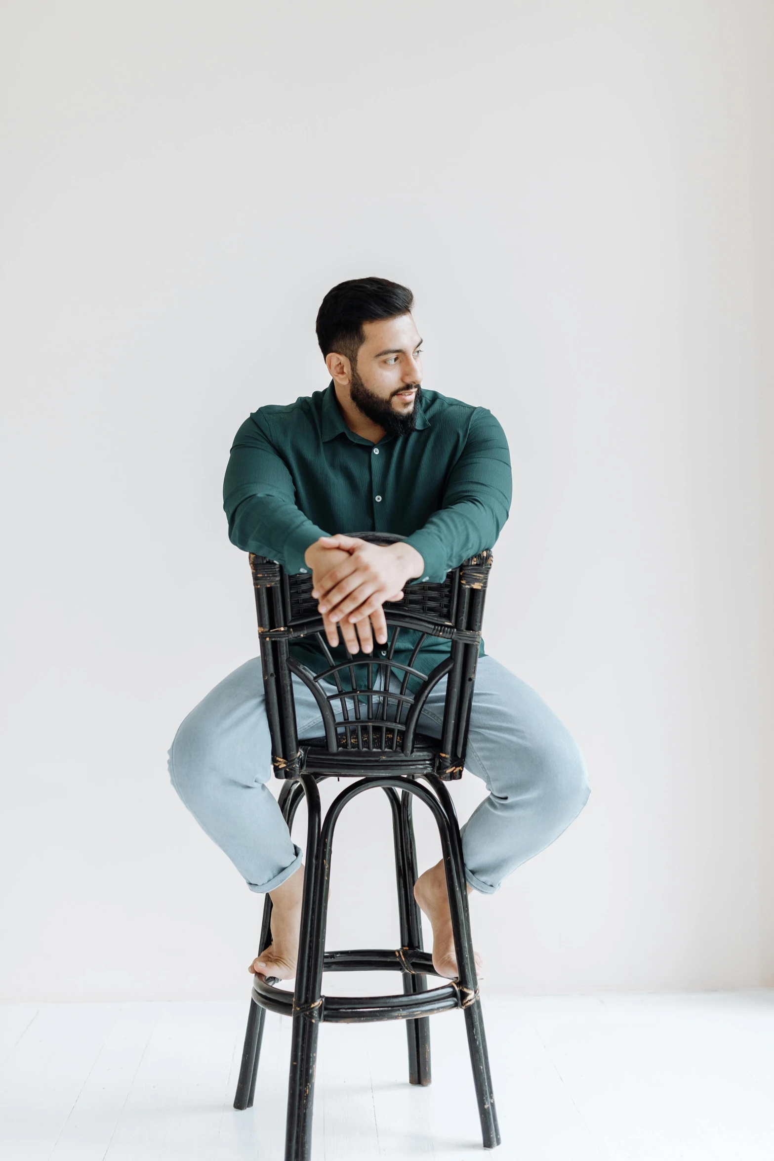 a man sitting in a black bar stool with his hands on the back