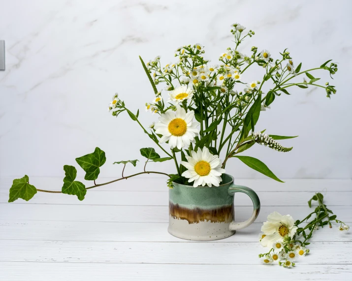 a green cup with yellow and white flowers