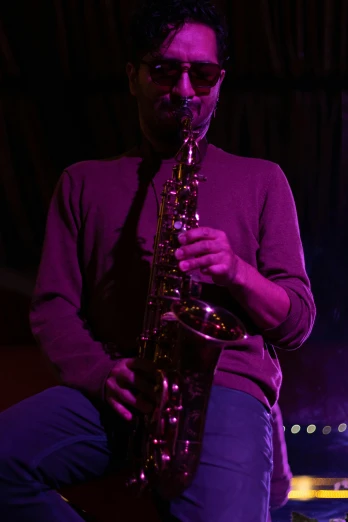 a man in sunglasses playing a saxophone on stage