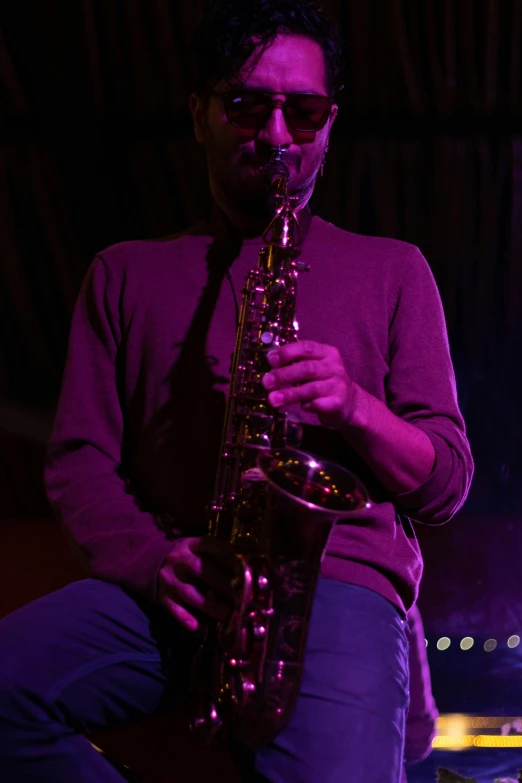 a man in sunglasses playing a saxophone on stage