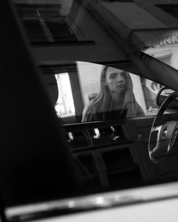 a girl sitting behind a car's steering wheel