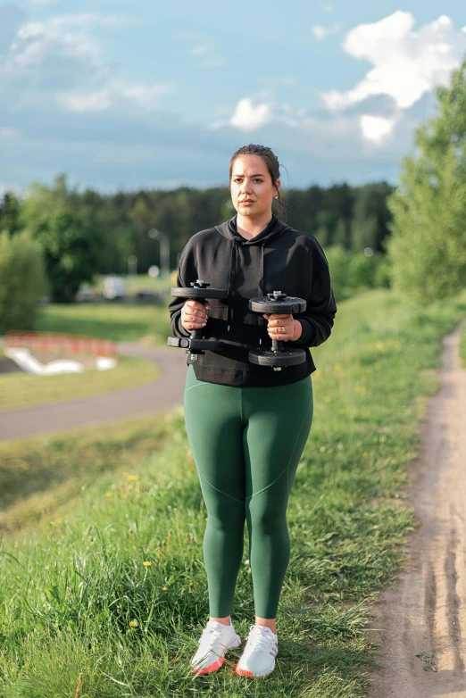 a woman holding two remotes standing on the grass