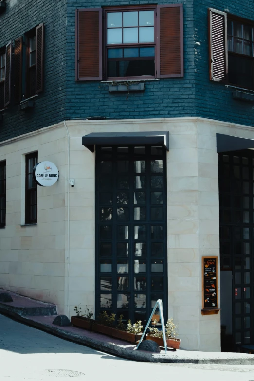 the sidewalk outside of a white building with brown shutters