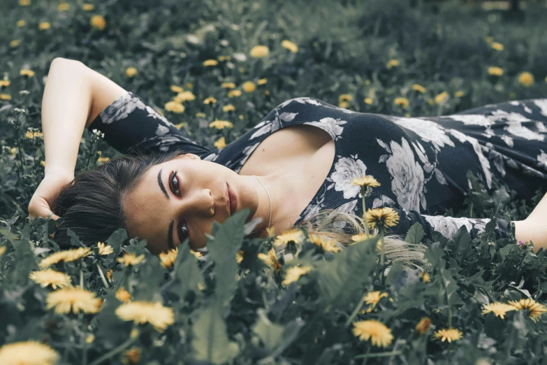 a woman laying on top of a lush green field