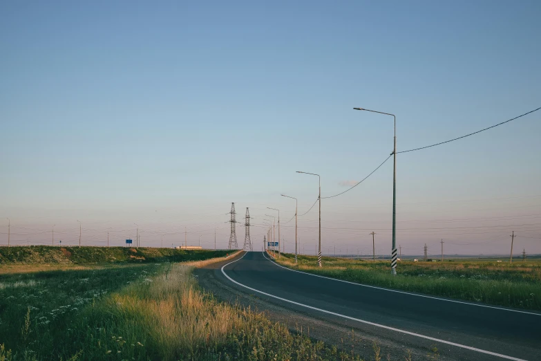 an empty road in the middle of a grass field