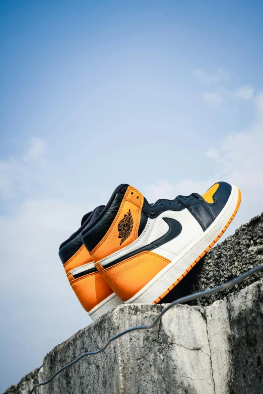 an orange and black nike sneaker on a cement wall