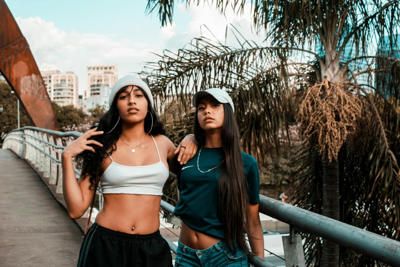 two girls on a bridge with their arms around one another