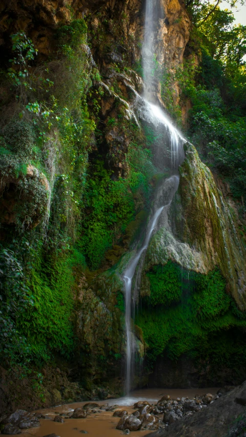 a waterfall with water cascading down it in the forest