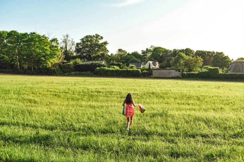 a little girl is running in a field with a frisbee