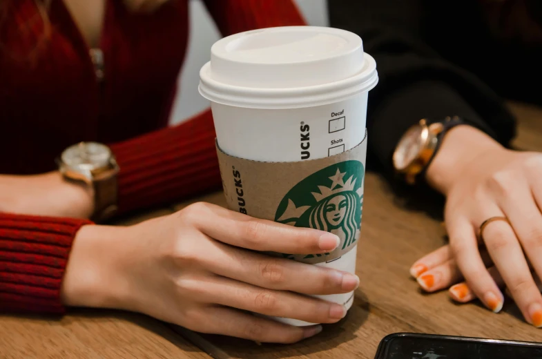 woman sitting at table holding up coffee cup