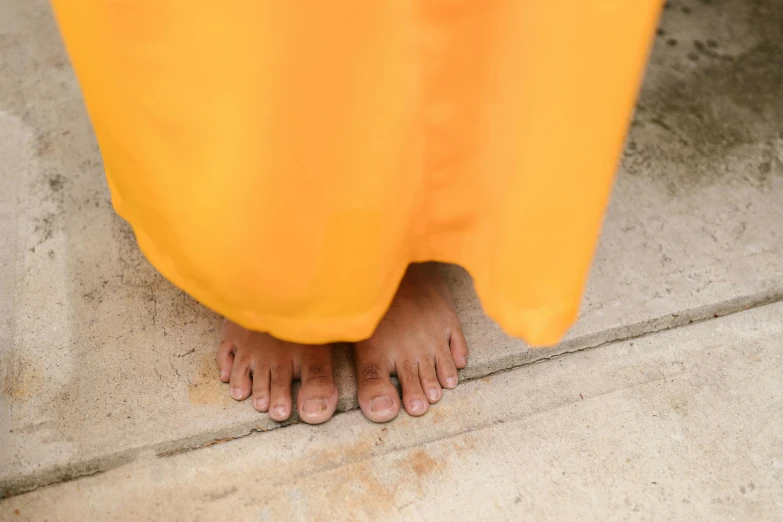 bare feet wearing yellow pants are standing on concrete