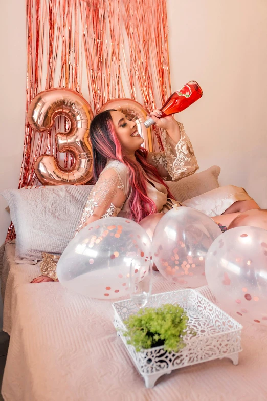 a woman lying down on a bed with balloons in the shape of letters