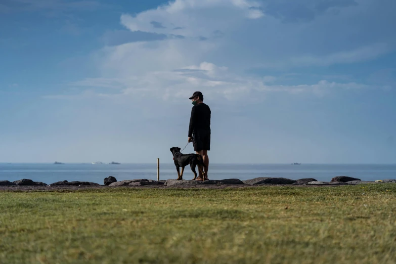 a man holding a dog looking out on the ocean