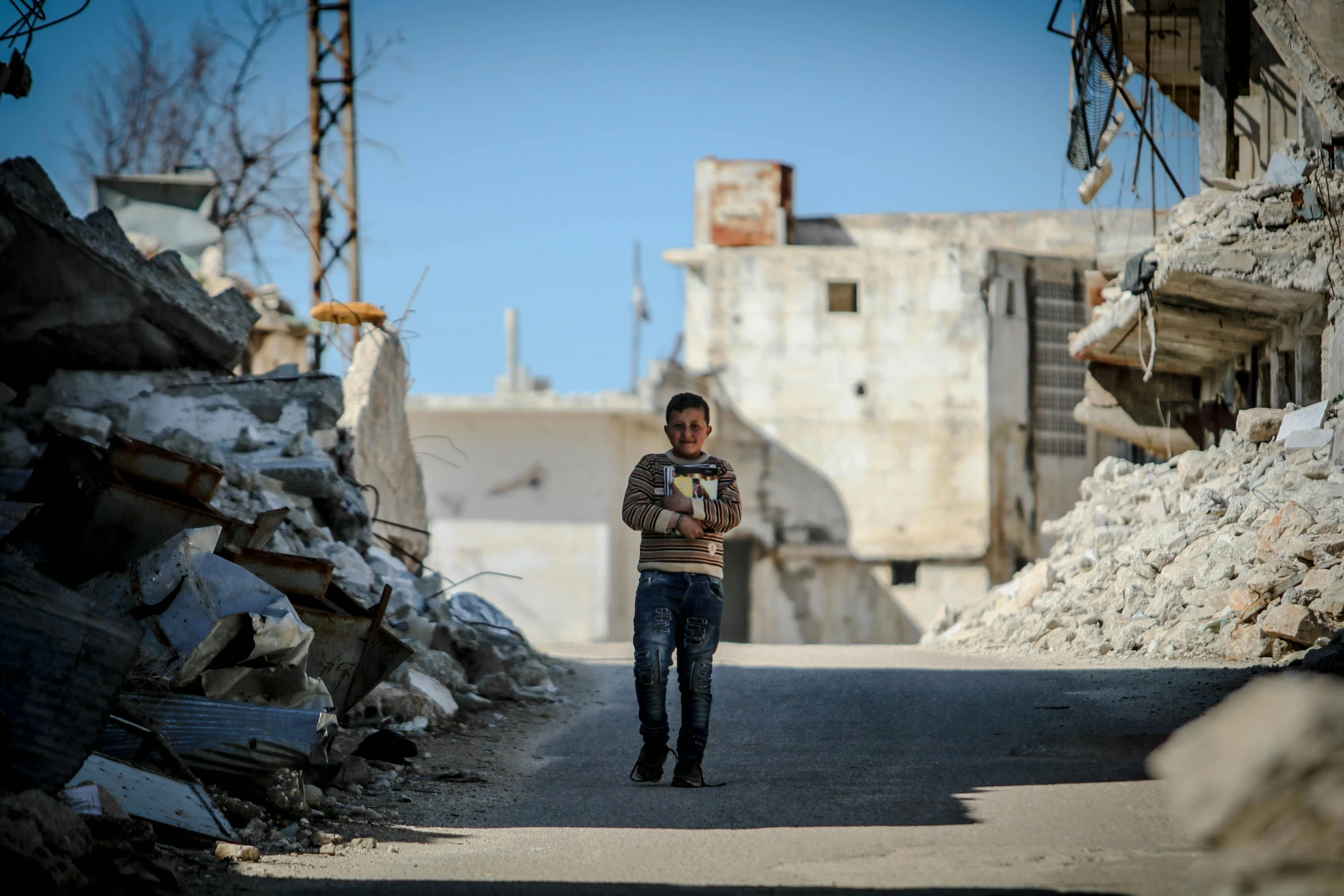 a boy stands in the street and looks up at soing behind him